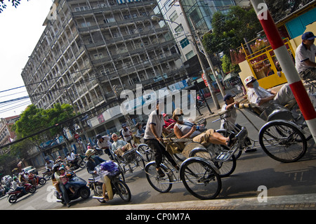 Horizontale Ansicht des Zyklus Rikschas, die westliche Touristen Tragen von Gesichtsmasken auf die Straßen von Ho Chi Minh City, Vietnam.