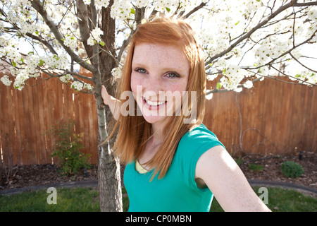 Fünfzehn Jahre altes Mädchen lächelnd und das Festhalten an weiße Birne Baum Blüte. Stockfoto