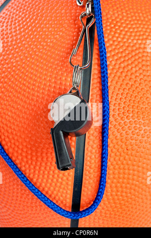 Ein Basketball die Schiedsrichterpfeife drapiert über eine orange, Kautschuk-Basketball. Gut für Sport Rückschlüsse wo Regeln wichtig sind. Stockfoto