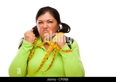 Attraktive frustriert Hispanic Frau gefesselt mit Maßband vor einem weißen Hintergrund. Stockfoto