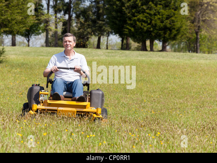 Senior pensionierter Mann, der den Rasen mäht und das Gras schneidet, Mann auf einem sitzenden Rasenmäher Stockfoto