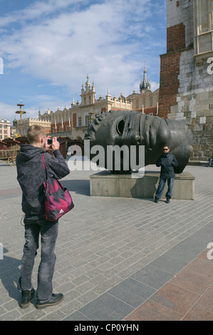 Touristische Bild vor dem Hintergrund einer Skulptur von Eros Bendato Skulptur von Igor Mitoraj in Town Square, Krakau, Po posing Stockfoto