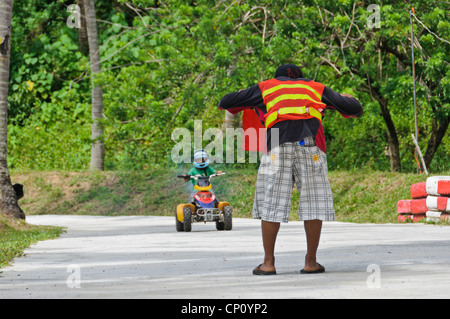 Verfolgen Sie Marschall stoppen kleiner Junge Reiten ATV mit roten Fahne - Adventure Park Puerto Galera Oriental Mindoro Philippinen Asien Stockfoto