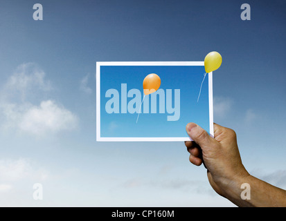 Hand halten Fotografieren mit Luftballons zu entkommen Stockfoto