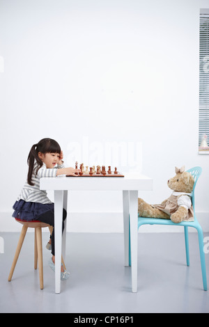 Ein Mädchen spielen Schachspiel mit Teddybär Stockfoto