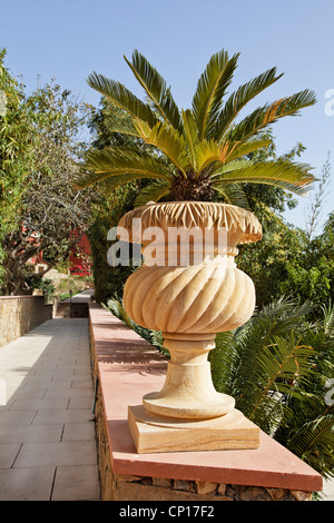 Generische indigenen Handwerk arbeiten Stein Garten Blume Topf Rand des zufälligen Steinmauer mit buschigen Grünpflanzen Pflaster als Kulisse Stockfoto