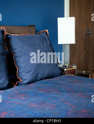 Blau und orange Kissen auf Bett in Addison Road, Großbritannien. Stockfoto