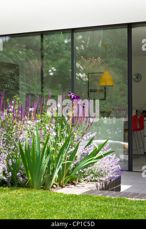 Angehoben, Bett, Terrasse und Glas-Schiebetüren, Küche/Essbereich vom Rasen im Garten hinter dem Haus gesehen Stockfoto