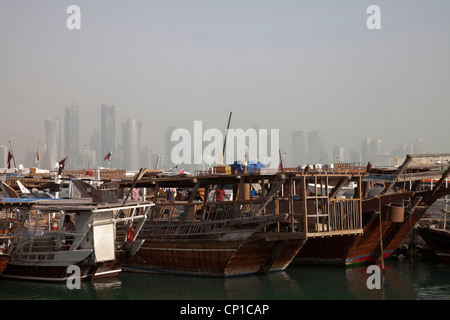 Traditionelle Boote im Hafen von Doha mit einer staubigen Skyline hinter. Stockfoto