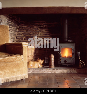 Gepolstertes Sofa vor Kaminofen in Inglenook Kamin Stockfoto