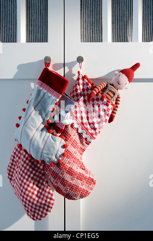 Childs rote und weiße Weihnachtsstrümpfe von Schranktür hängen Stockfoto