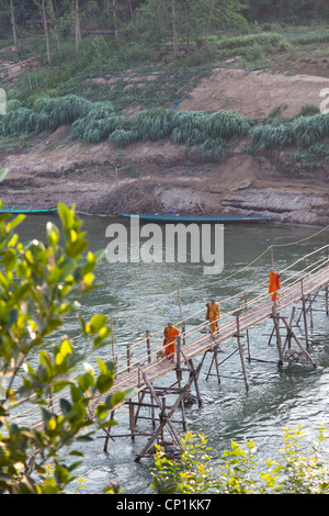 Novizen mit der fadenscheinigen Bambus Fußgängerbrücke über den Khan River, einem Nebenfluss des Mekong (Luang Prabang - Laos) geworfen. Stockfoto