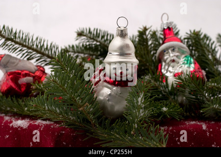 Weihnachtsschmuck in einem Bett aus Frasier Tannenzweigen mit Schnee. Stockfoto