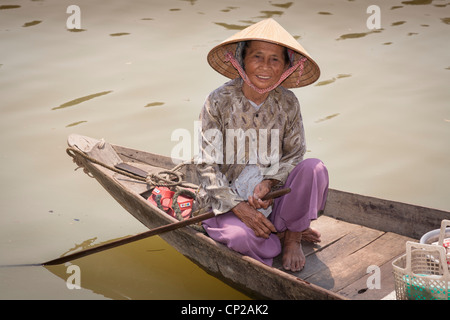 Eine alte vietnamesische Frau, sitzt in einem kleinen Holzboot, Hoi An, Provinz Quang Nam, Vietnam Stockfoto