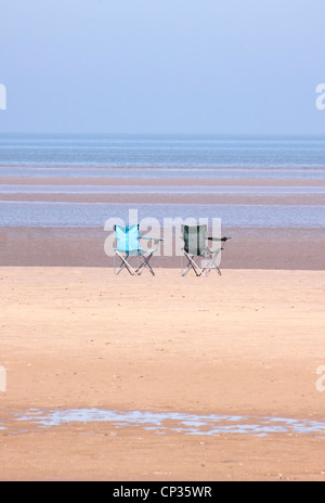 EIN PAAR LEERE STÜHLE AM WEITEN STRAND VON BRANCASTER IN NORTH NORFOLK. UK Stockfoto