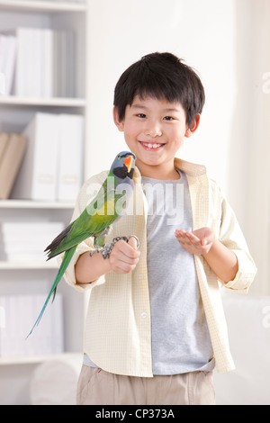 Kleiner Junge spielt mit einem Papagei Stockfoto