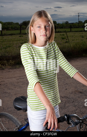 Elf Jahre altes Mädchen auf ihrem Fahrrad auf Feldweg. Stockfoto