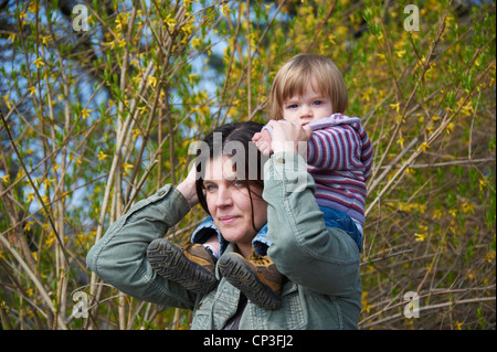 Mutter mit Kind Baby Mädchen Tochter auf Schultern im Park im Frühjahr Stockfoto