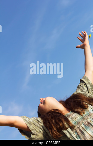 Anbetung der Sonne - glückliche junge Teenager Frau mit geöffneten Armen frei zu fühlen. Sonnige Sommer im Freien Schuss vor einem strahlend blauen Himmel. Stockfoto