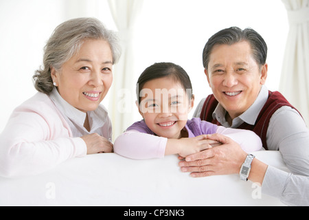 Chinesische Großeltern und Gradaughter umzudrehen und lächelnd auf dem Sofa im Wohnzimmer Stockfoto