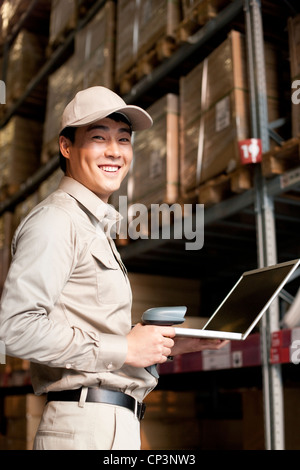 Männliche chinesische Lagerarbeiter mit Laptop und scanner Stockfoto