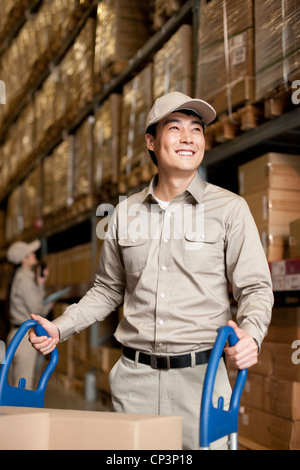 Männliche chinesische Lager Arbeiter Kisten schieben Stockfoto