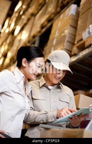 Chinesische Unternehmerin in einem Lager mit Arbeiter mit einem laptop Stockfoto