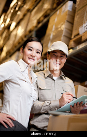Chinesische Unternehmerin in einem Lager mit Arbeiter Stockfoto