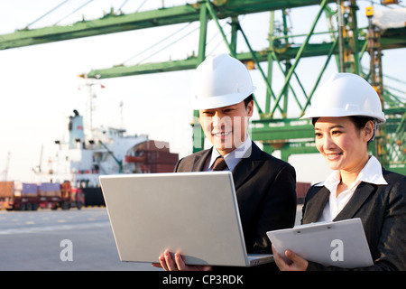 Geschäftsleute, die mit einem Laptop in einem Versand-Hafen Stockfoto