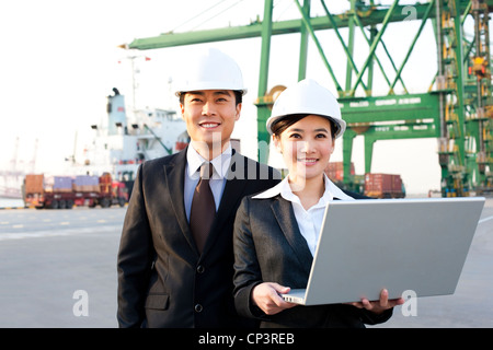 Geschäftsleute, die mit einem Laptop in einem Versand-Hafen Stockfoto