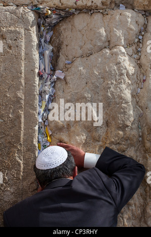 Jüdischer Mann betet neben einen Riss voller Briefe mit schriftlichen Gebet an der Klagemauer in Jerusalem. Israel Stockfoto