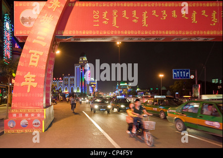 Motorräder, Fahrräder und Autos Fahrt entlang einer der wichtigsten Straßen in Hohhot mit Bewegung Unschärfe in der Abenddämmerung. Stockfoto