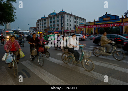 Motorräder, Fahrräder und Autos Fahrt entlang einer der wichtigsten Straßen in Hohhot mit Bewegung verwischen und Blitz in der Abenddämmerung zu füllen. Stockfoto