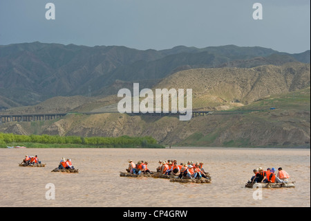 Chinesische Touristen reisen entlang des gelben Flusses auf traditionelle Schaffell Flößen - eines der "Fahrten" im Shapatou Themenpark. Stockfoto