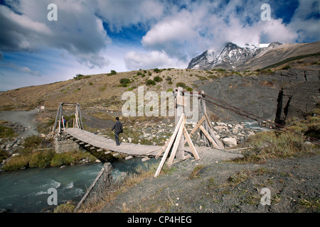 Wanderer, überqueren eine kleine Brücke auf eine Spur im Torres Del Paine Nationalpark Monte Almirante Nieto in der Ferne. Stockfoto