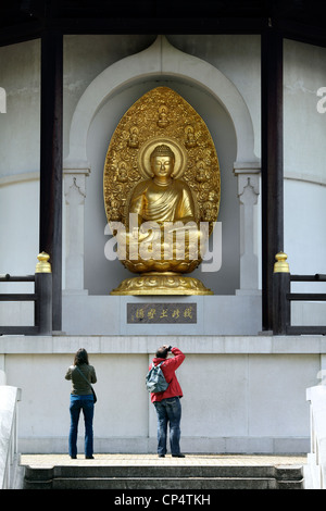 Menschen fotografieren eine vergoldete Bronze-Skulptur des Buddha an der Friedenspagode, Battersea Park, London. Stockfoto