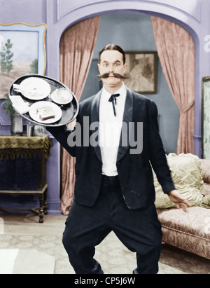 Kellner im Hotelzimmer versucht, Tablett zu balancieren Stockfoto