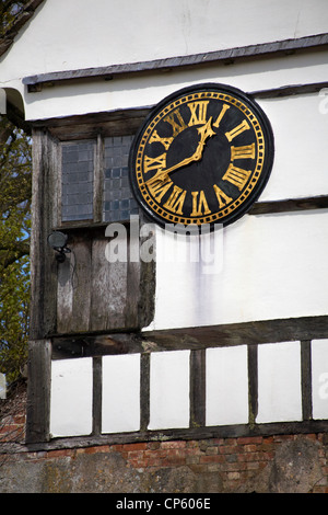 Zifferblatt mit römischen Ziffern, die im April auf dem Uhrturm-Fachwerkgebäude in Lacock, Wiltshire, Großbritannien, Zinken 12:40 zeigen Stockfoto