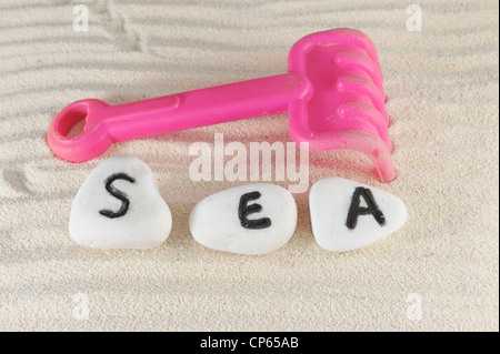 Meer-Wort auf Gruppe von Steinen mit Sand als Hintergrund Stockfoto