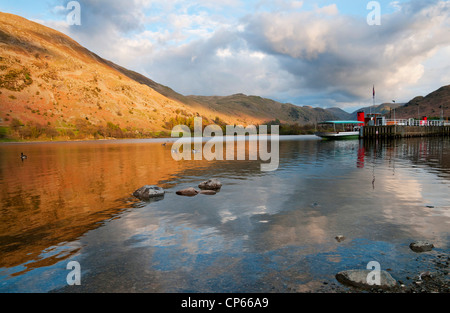 Boote am Glenridding Pier für den Abend, sonnenbeschienenen Fells spiegelt sich im Wasser, Ullswater, Lake District, Cumbria, UK Stockfoto