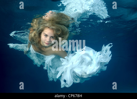 Eine junge Frau mit großen Haar posiert in einem Pool unter Wasser Stockfoto