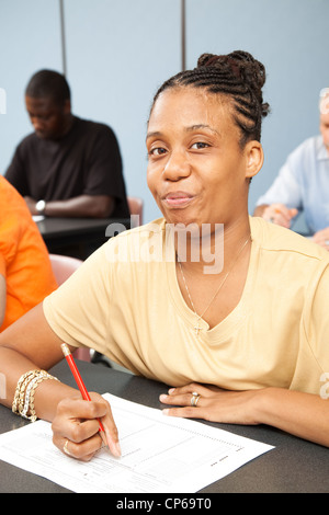 Hübsche Student mit Zerebralparese, er einen Test in ihrer Klasse der Erwachsenenbildung. Stockfoto