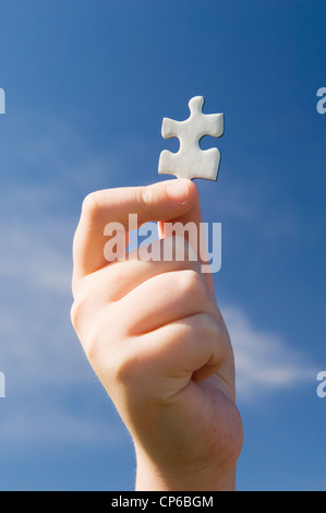 Des Kindes Hand hält eine einzelne Puzzleteil. Stockfoto