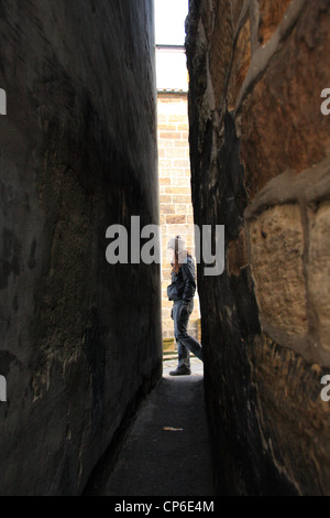 Frau Waler übergibt die schmalste Gasse im Vereinigten Königreich - als Hund Loup, Staithes, North Yorkshire, England, UK Stockfoto