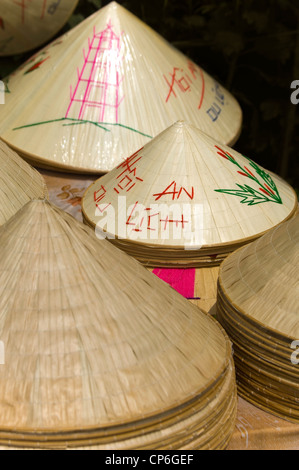 Vertikale Nahaufnahme von Haufen von Nón Lá, Non la, die traditionelle kegelförmige Strohhüte getragen von vielen in Vietnam. Stockfoto