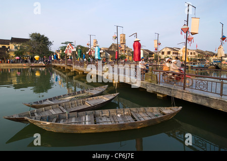 Horizontale Ansicht von Booten und dekorierten Thu Bồn Flussbrücke spiegelt sich im Wasser im Zentrum von Hoi an Old Town. Stockfoto