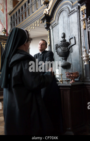 Ein Priester im Gespräch mit einer Nonne in der Sakristei der Basilika Corpus Christi, Krakau, Polen Stockfoto