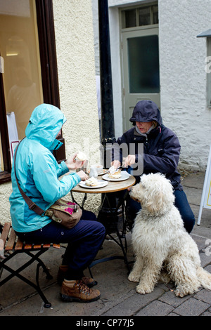 Wanderer haben einen Cream Tea außerhalb mit ihrem Hund auf außen Café in Ash Street Bowness auf Windermere Stockfoto