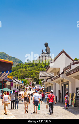 Besucher in der Hauptstraße von Ngong Ping auf Lantau Island, Hong Kong, von der Tian Tan Buddha-Statue dominiert. Stockfoto