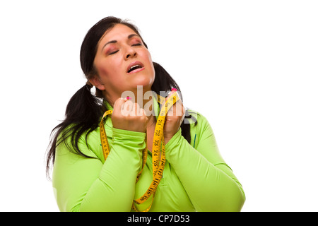 Attraktive frustriert Hispanic Frau mit Maßband vor einem weißen Hintergrund. Stockfoto